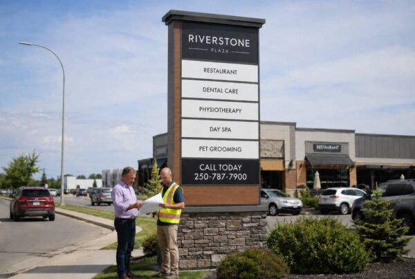 Plan a Pylon Sign with a property owner and sign professional reviewing plans beside a multi-tenant roadside pylon sign featuring a “Call Today” CTA and 250-787-7900.