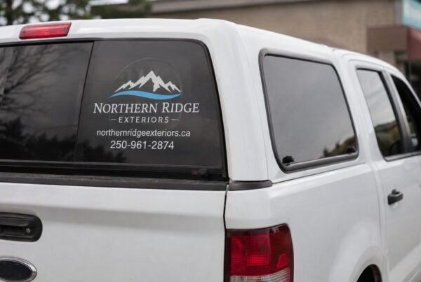 White truck displaying a custom vinyl decal for car windows with business contact info.