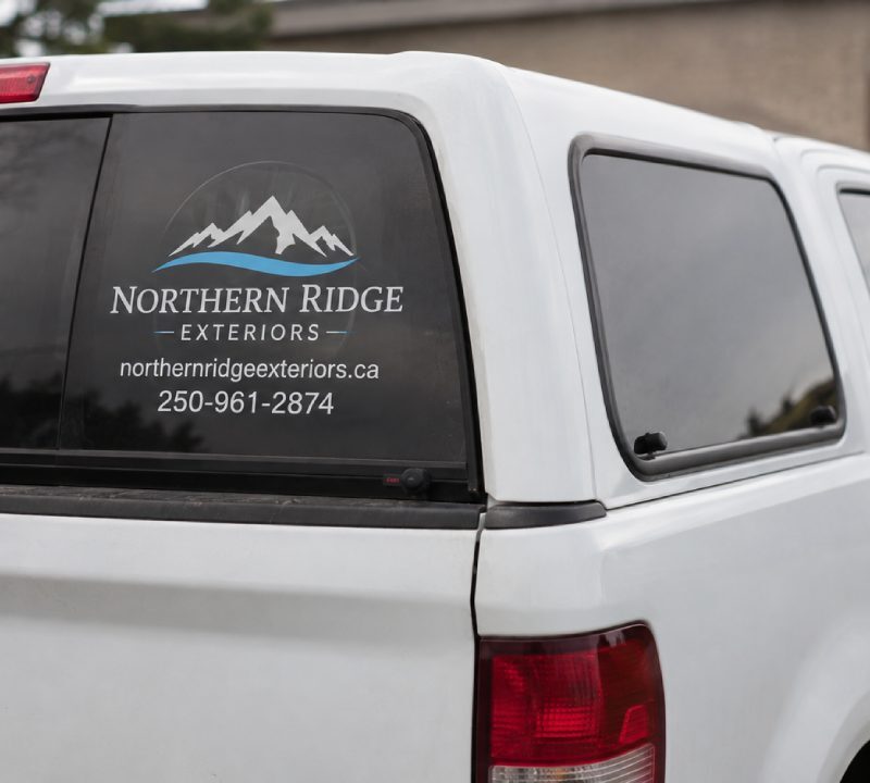 White truck displaying a custom vinyl decal for car windows with business contact info.